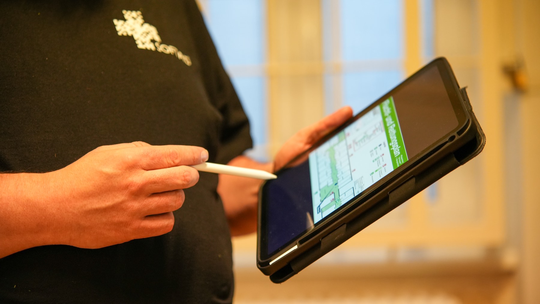 Ein SoftAid-Mitarbeiter hält ein Tablet mit einem Flucht- und Rettungsplan